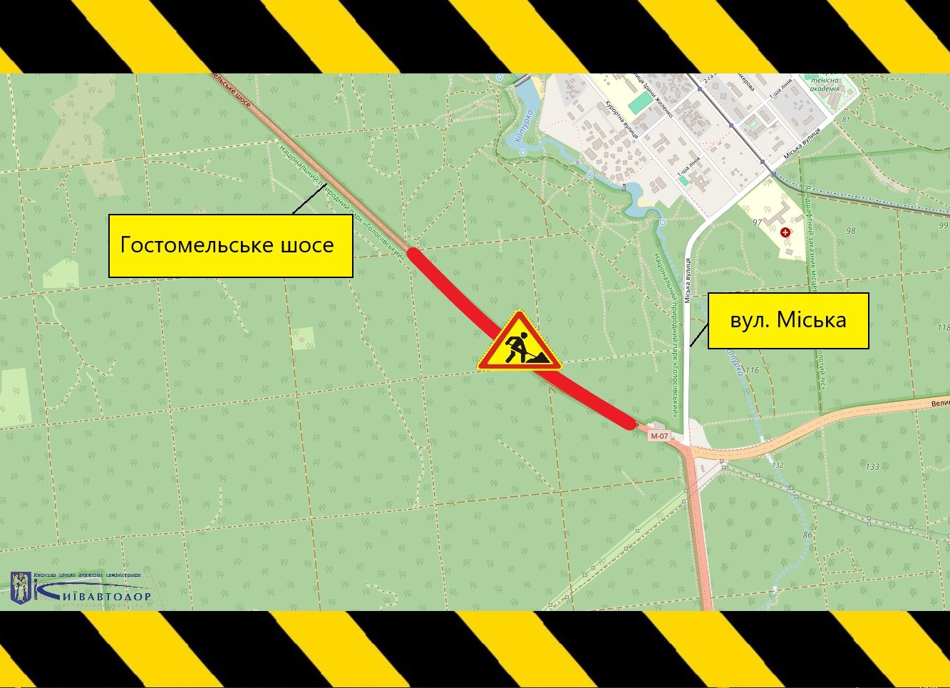 Схема організації дорожнього руху на карті лісової місцевості в районі Гостомельського шосе та вулиці Міської. Ділянка проведення дорожніх робіт позначена широкою червоною лінією вздовж частини Гостомельського шосе. У центрі ремонтної зони розміщено попереджувальний дорожній знак «Дорожні роботи». На карті підписані основні орієнтири — Гостомельське шосе та вулиця Міська. По верхньому та нижньому краях схеми розташовані жовто-чорні попереджувальні смуги, що вказують на тимчасові обмеження руху через ремонтні роботи.