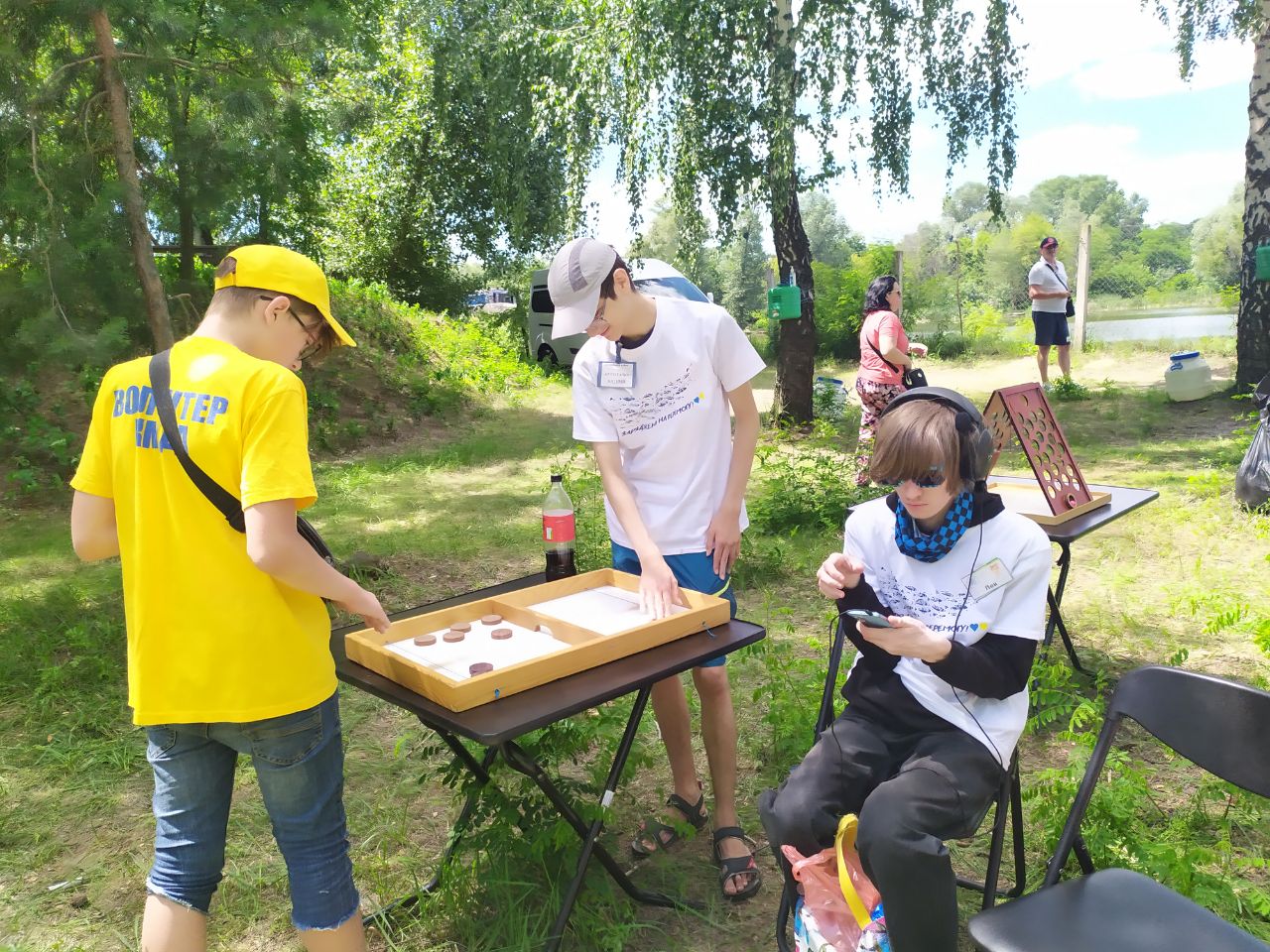 На фото волонтер Іван з учасникам фестивалю грається у настільну гру